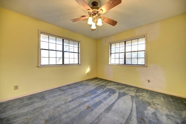 carpeted empty room with ceiling fan and plenty of natural light