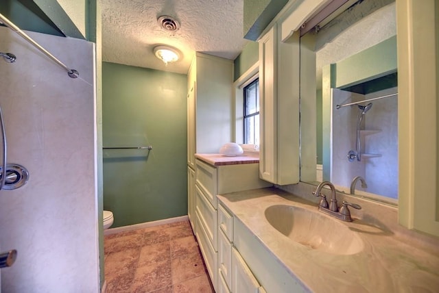 bathroom featuring vanity, toilet, a textured ceiling, and walk in shower