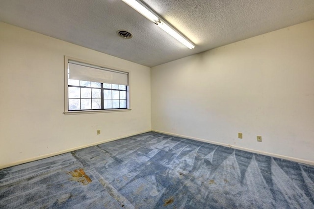 carpeted empty room featuring a textured ceiling