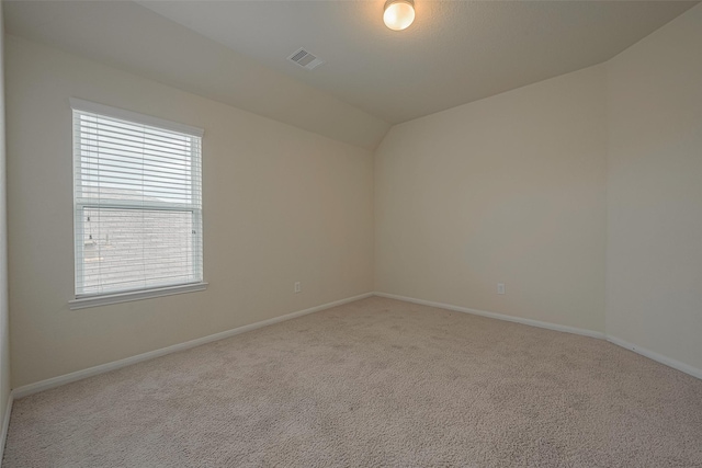 carpeted empty room featuring vaulted ceiling