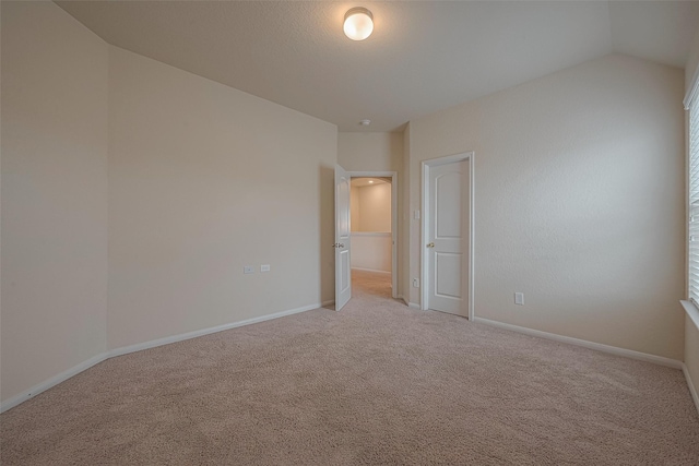 empty room with light colored carpet and lofted ceiling