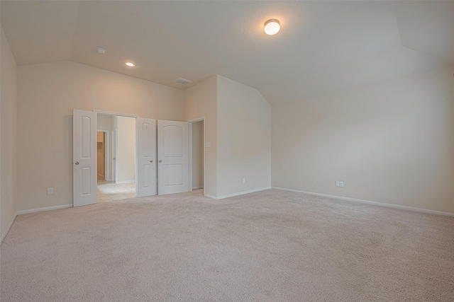 carpeted empty room with vaulted ceiling