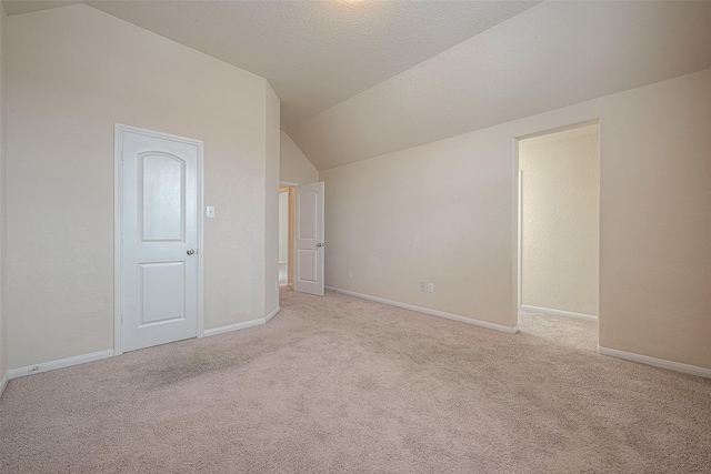 interior space with light colored carpet, lofted ceiling, and a textured ceiling