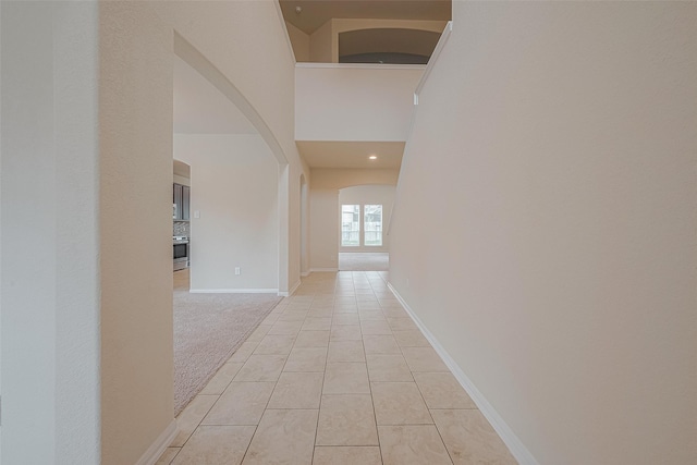 corridor featuring a towering ceiling and light colored carpet