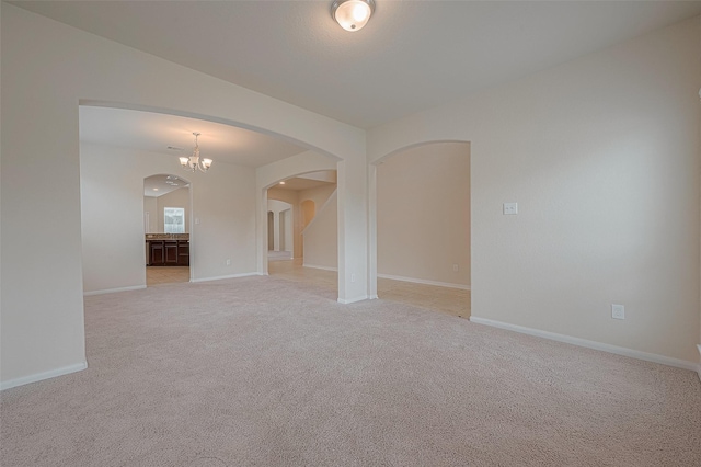 empty room featuring light carpet and a chandelier