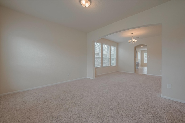 empty room with light colored carpet and a chandelier