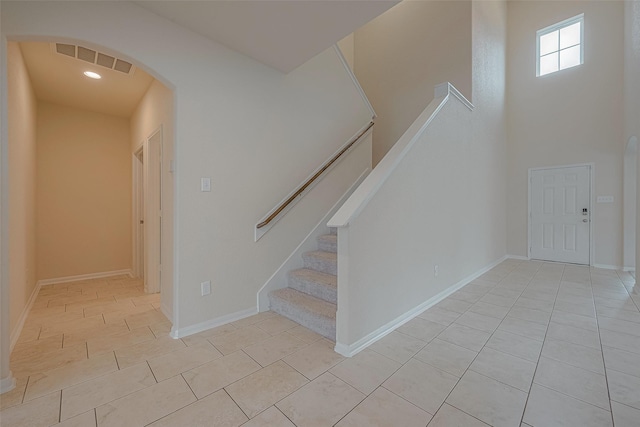 stairs with tile patterned flooring and a towering ceiling