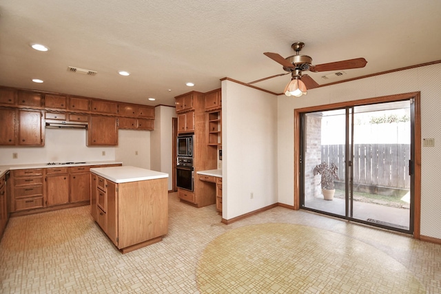 kitchen featuring oven, ceiling fan, ornamental molding, a kitchen island, and cooktop