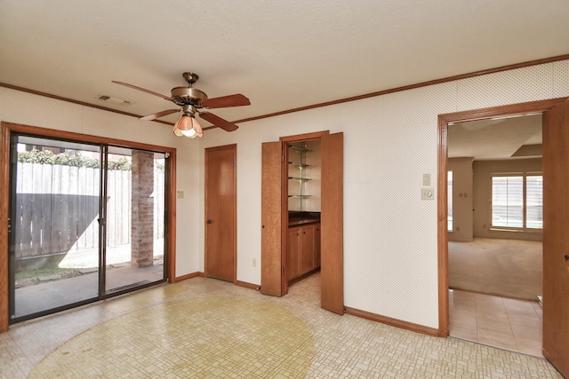 empty room featuring ceiling fan, crown molding, and a wealth of natural light