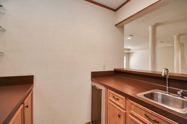 kitchen with ornate columns, crown molding, and sink