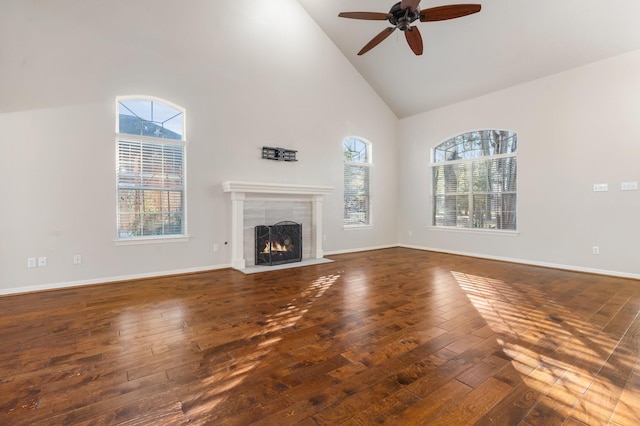 unfurnished living room featuring a tile fireplace, high vaulted ceiling, ceiling fan, and dark hardwood / wood-style floors