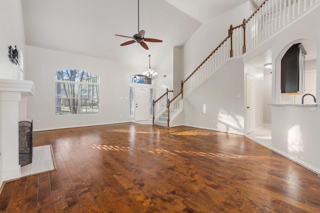 unfurnished living room featuring sink, ceiling fan with notable chandelier, high vaulted ceiling, and dark hardwood / wood-style floors