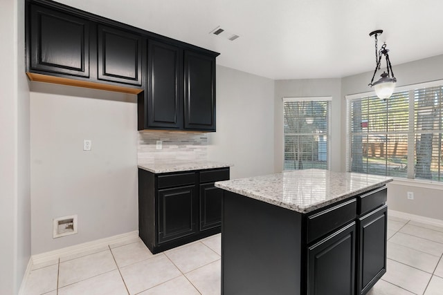 kitchen with light stone countertops, hanging light fixtures, a center island, decorative backsplash, and light tile patterned flooring