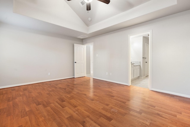 empty room with lofted ceiling, ceiling fan, light hardwood / wood-style floors, and a tray ceiling