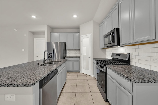 kitchen featuring gray cabinetry, sink, light tile patterned floors, an island with sink, and stainless steel appliances