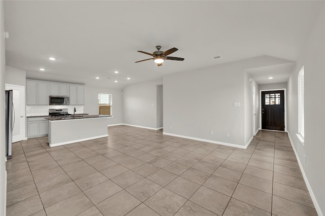 unfurnished living room featuring sink, ceiling fan, a healthy amount of sunlight, and light tile patterned flooring