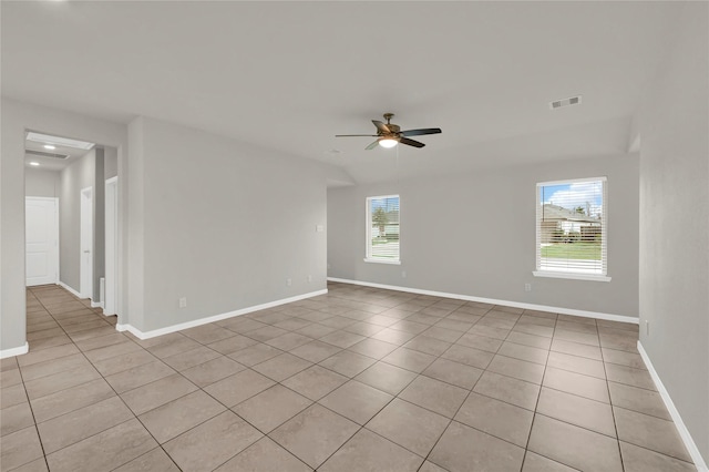 tiled empty room with a wealth of natural light and ceiling fan