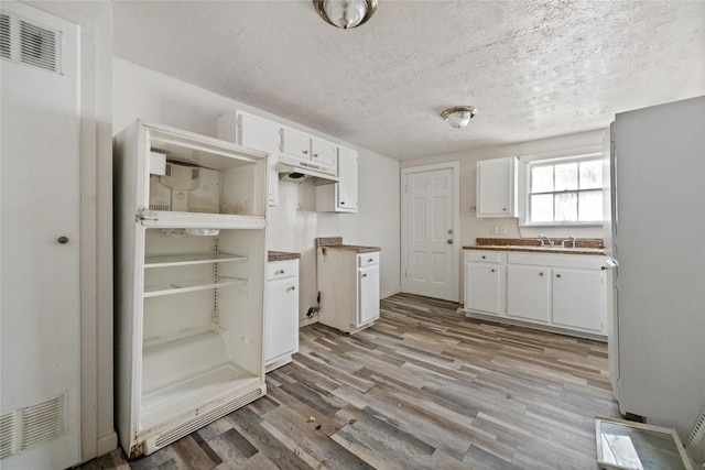 kitchen with light hardwood / wood-style floors, sink, white cabinetry, and a textured ceiling