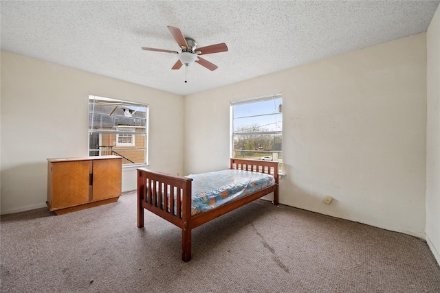 bedroom with ceiling fan, a textured ceiling, and light carpet