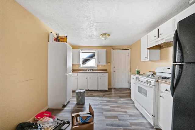 kitchen featuring sink, white appliances, white cabinetry, hardwood / wood-style flooring, and a textured ceiling