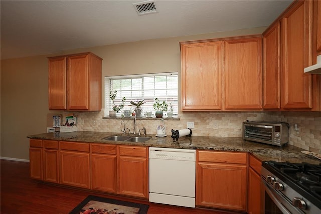 kitchen featuring white dishwasher, dark hardwood / wood-style flooring, sink, and dark stone counters