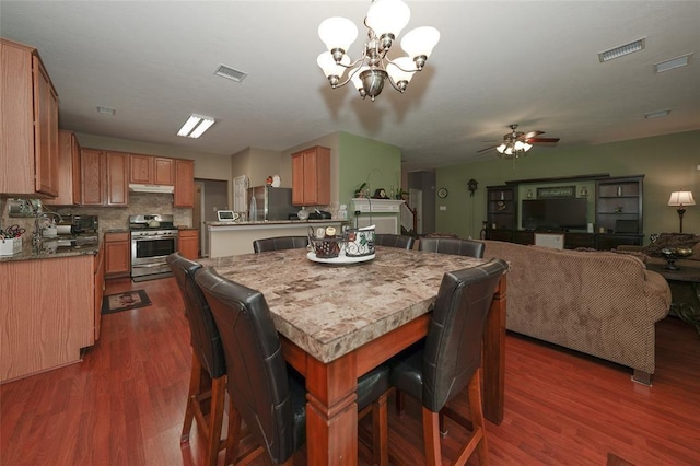 dining space featuring ceiling fan with notable chandelier, dark wood-type flooring, and sink