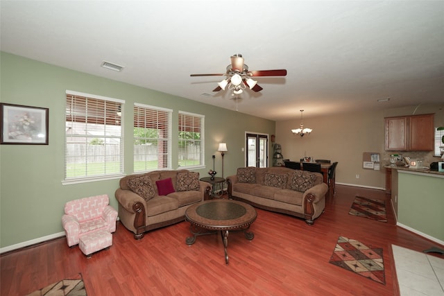 living room featuring ceiling fan with notable chandelier and light hardwood / wood-style flooring