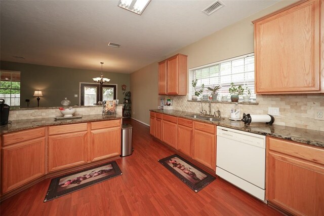 kitchen with sink, dishwasher, hanging light fixtures, a notable chandelier, and dark stone countertops