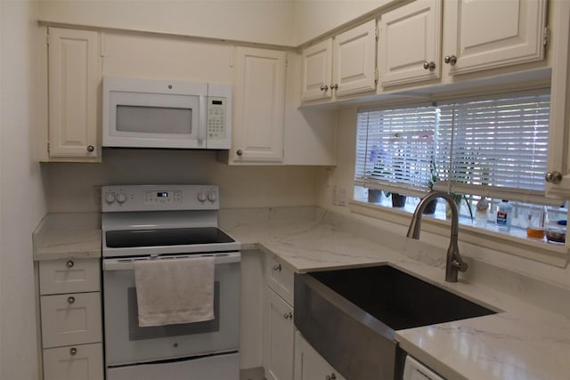 kitchen with white appliances, light stone counters, white cabinetry, and sink