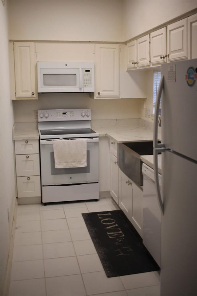 kitchen featuring white appliances, white cabinetry, and light tile patterned flooring