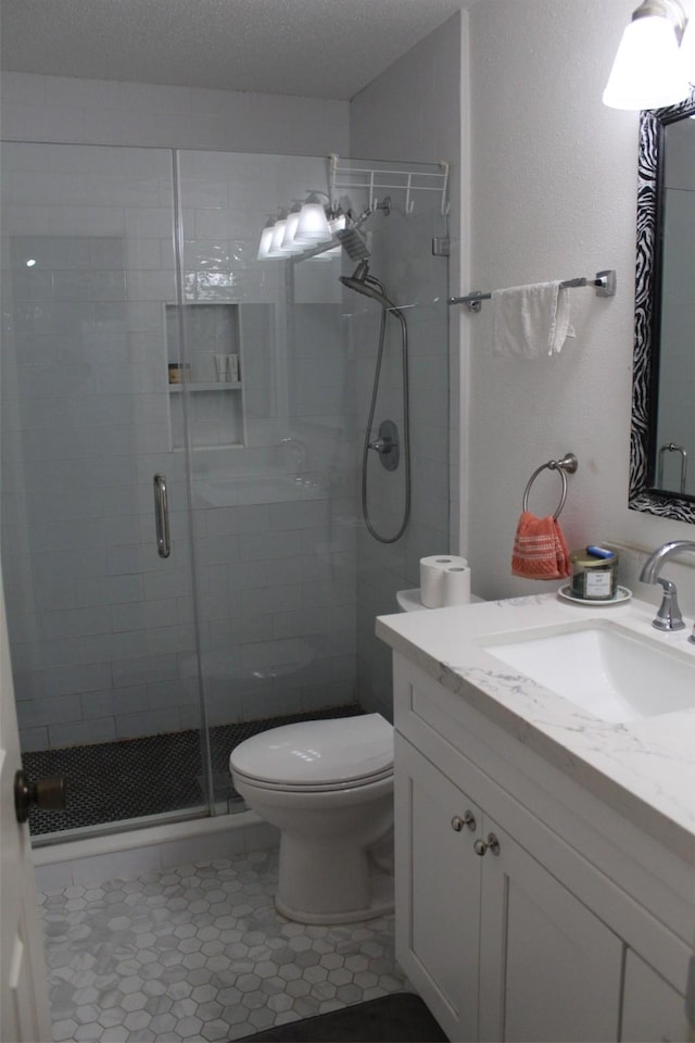 bathroom featuring vanity, a shower with door, tile patterned flooring, toilet, and a textured ceiling