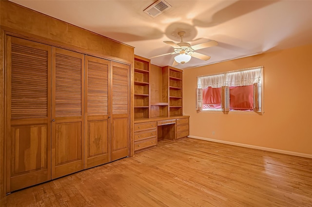 unfurnished bedroom featuring light wood-type flooring, ceiling fan, and built in desk