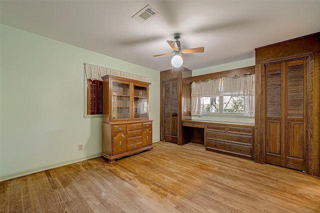 unfurnished bedroom featuring ceiling fan, built in desk, and light wood-type flooring