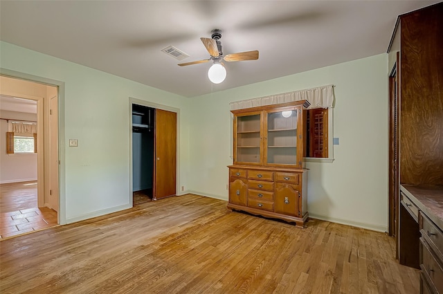 unfurnished bedroom featuring ceiling fan, light hardwood / wood-style floors, and a closet