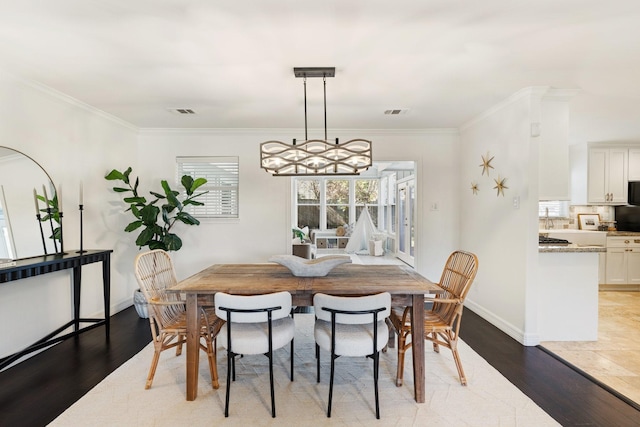 dining room with crown molding, a chandelier, and light wood-type flooring