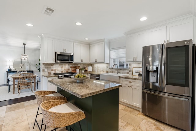 kitchen with pendant lighting, a kitchen island, white cabinets, and appliances with stainless steel finishes