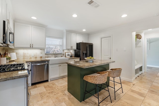 kitchen with white cabinets, appliances with stainless steel finishes, a center island, and sink