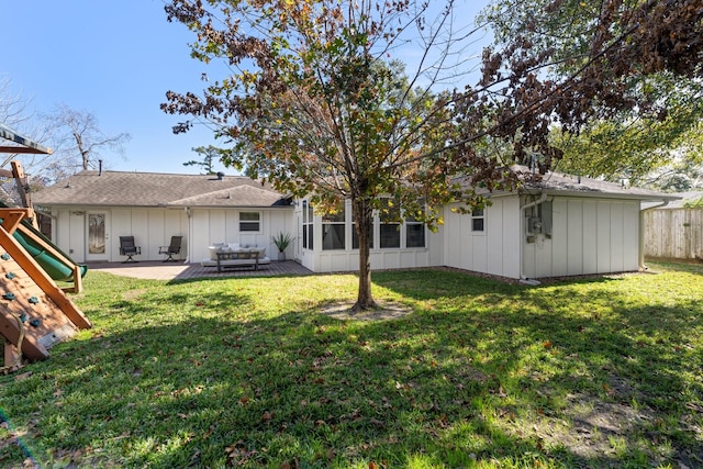 rear view of house with a playground, a yard, and a patio