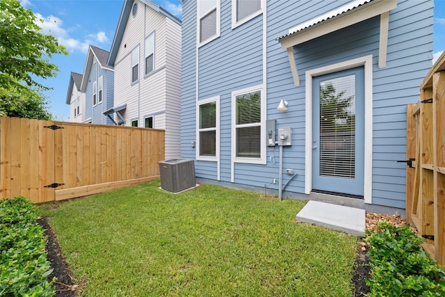 doorway to property with central air condition unit and a lawn