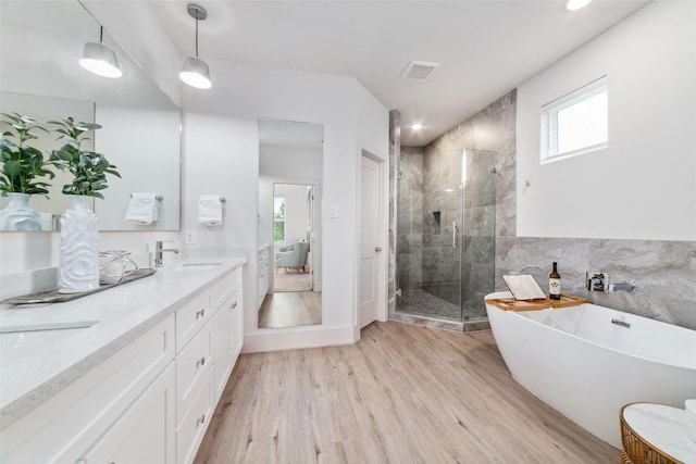 bathroom with a wealth of natural light, vanity, shower with separate bathtub, and hardwood / wood-style flooring