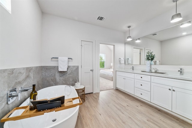 bathroom featuring vanity, a bath, tile walls, and hardwood / wood-style flooring