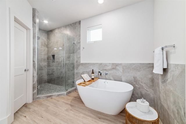 bathroom featuring hardwood / wood-style floors, shower with separate bathtub, and tile walls