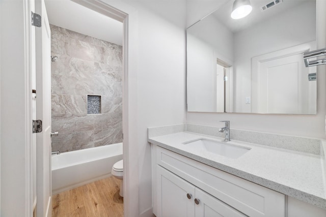 full bathroom featuring vanity, hardwood / wood-style flooring, toilet, and tiled shower / bath