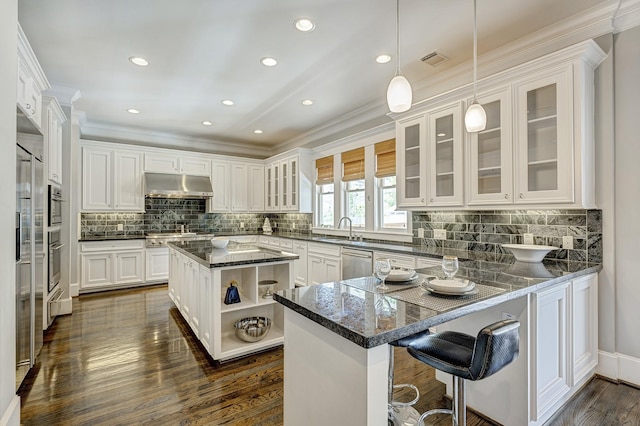 kitchen with stainless steel appliances, dark stone counters, white cabinets, and a kitchen island