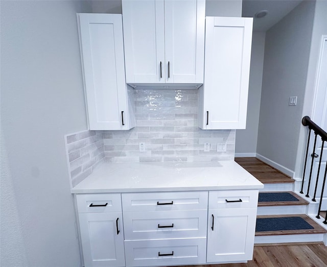 kitchen with backsplash, light stone counters, and white cabinets