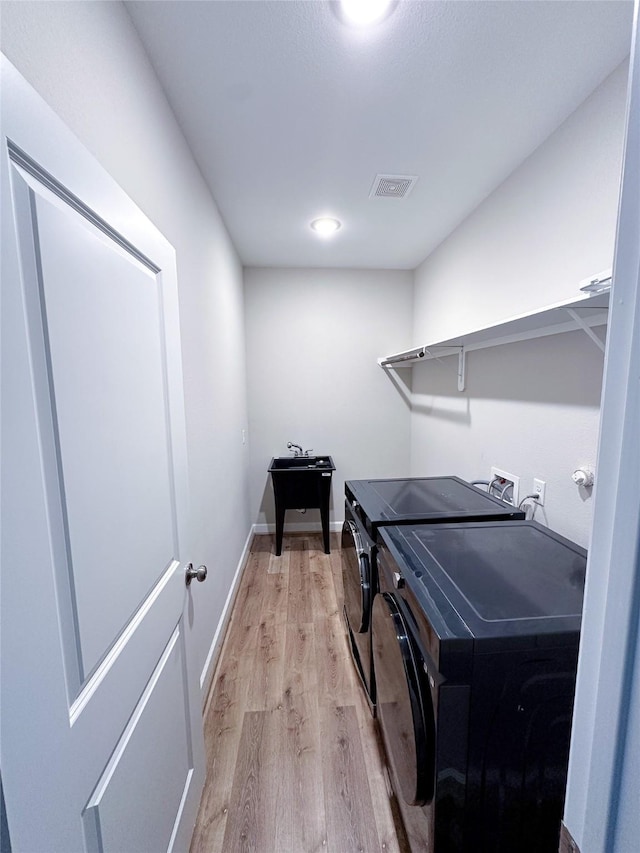 laundry area featuring light wood-type flooring and washer and clothes dryer