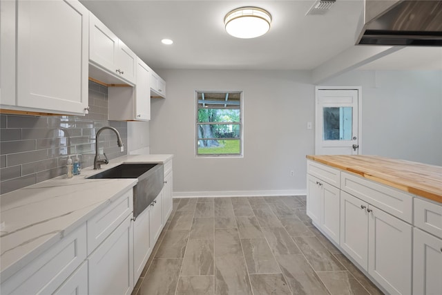 kitchen with white cabinets, backsplash, butcher block countertops, and sink