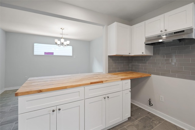 kitchen with white cabinetry, decorative backsplash, decorative light fixtures, and wood counters