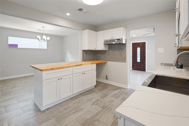 kitchen featuring backsplash, white cabinetry, and wood counters