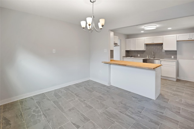 kitchen with white cabinets, wooden counters, and decorative light fixtures